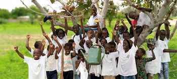 Kinder stehen vor einem Baum auf dem Gelände der Pflanzaktion.