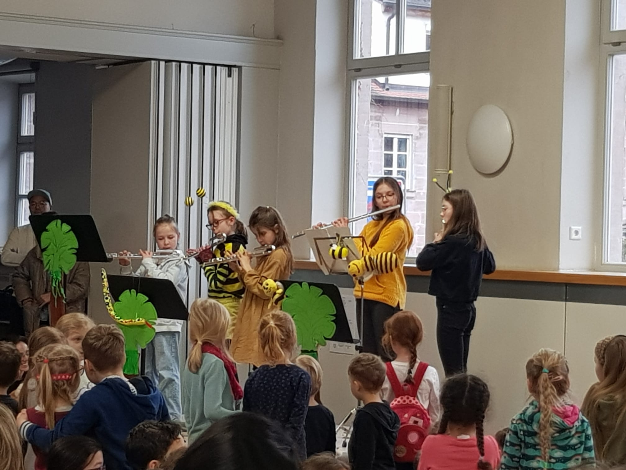Schülerinnen als Bienen verkleidet spielen Querflöte