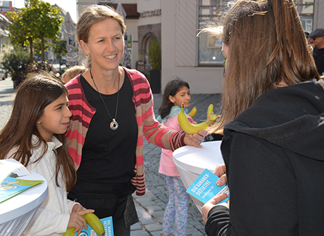 Lehrerin Claudia Svarovsky verteilt mit einer Schülerin Faire Bananen.