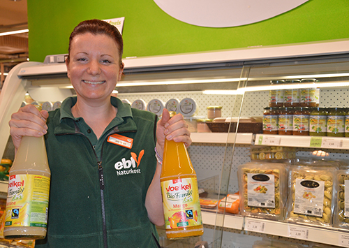 Ebl-Mitarbeiterin zeigt Fairtrade-Saftflaschen