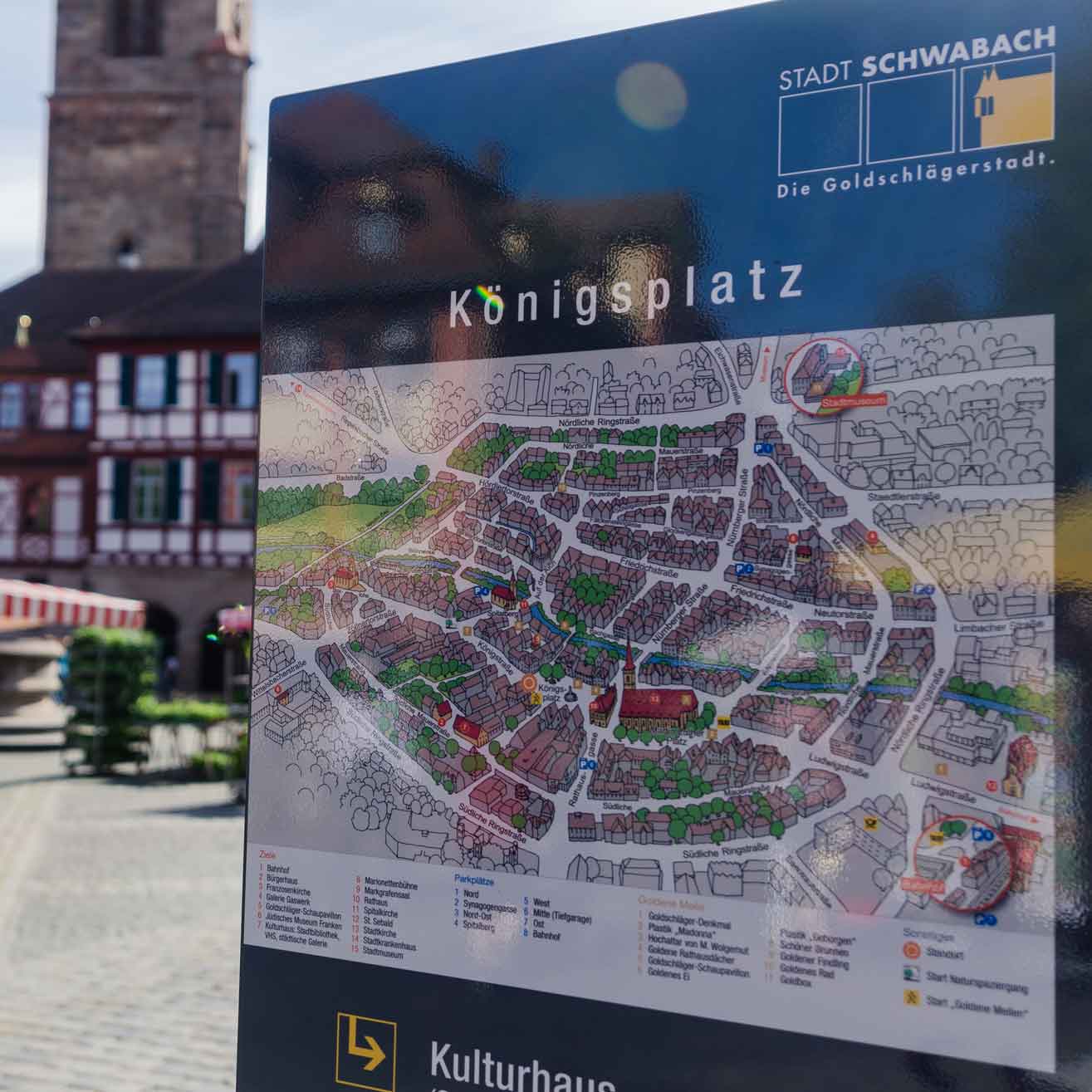 Marktplatz mit Wegweiser im Vordergrund