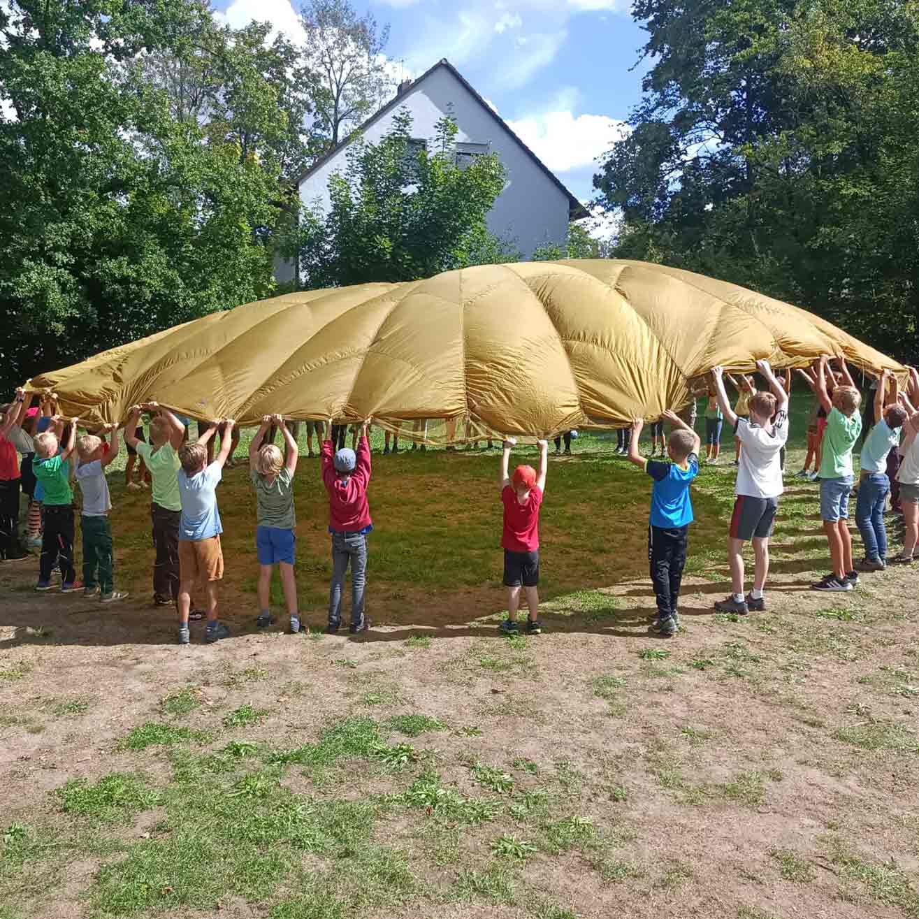 Kinder unter einem Ballontuch auf dem Aktivspielplatz