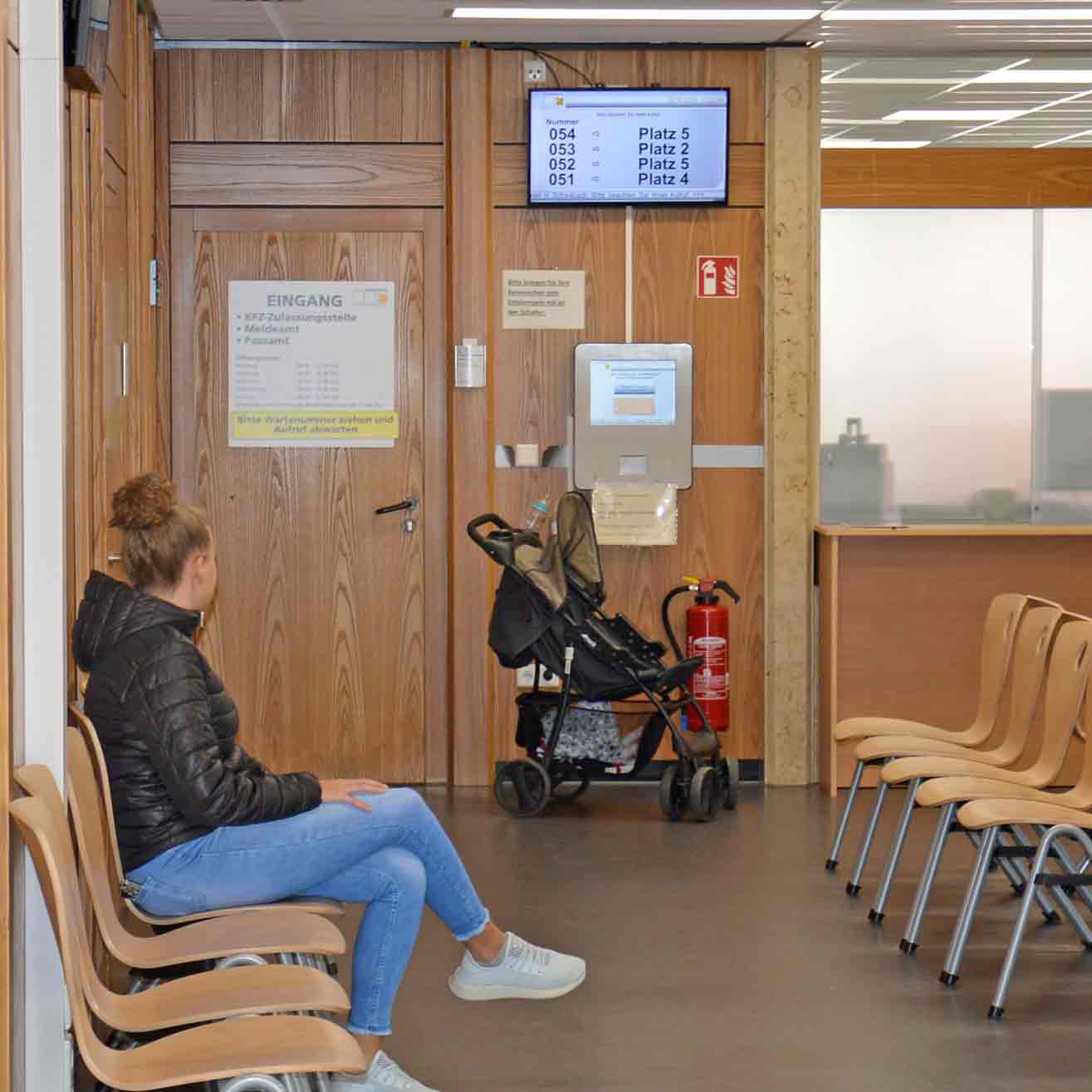 Junge Frau im Warteraum des Meldeamtes